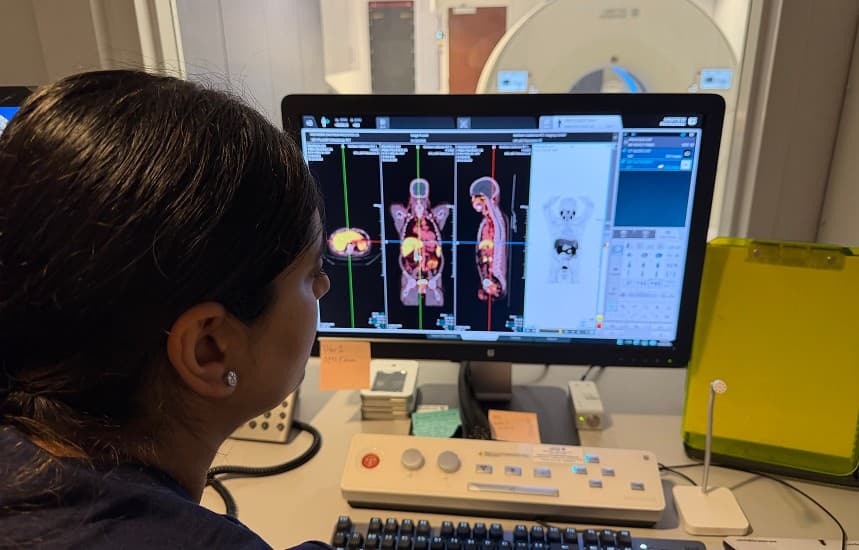 An NCPIC technologist reviewing PET/CT images at the scanner workstation