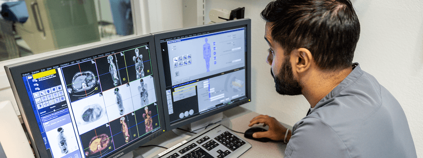 NCPIC technologist reviewing PET/CT images at a diagnostic workstation